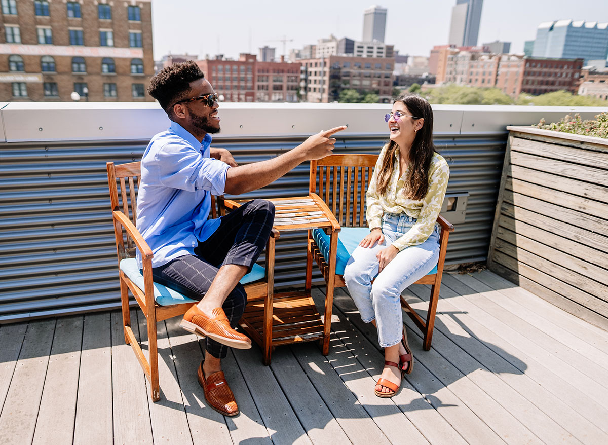 two friends sitting on a patio having a conversation overlooking Omaha's skyline
